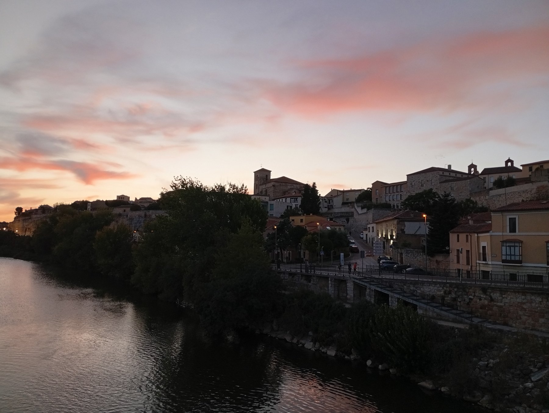 Zamora sobre la peña al atardecer, vista desde el Puente de Piedra, con el Duero en primer plano.